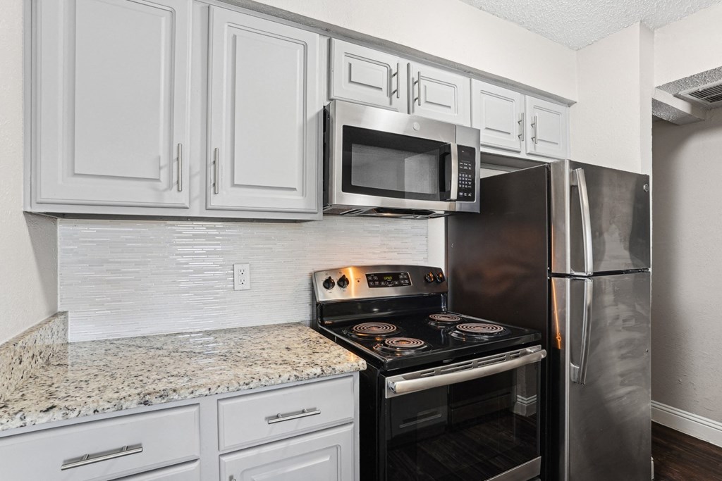 B1 kitchen with a black stove top oven and white cupboards at Vine Apartments in Arlington, TX