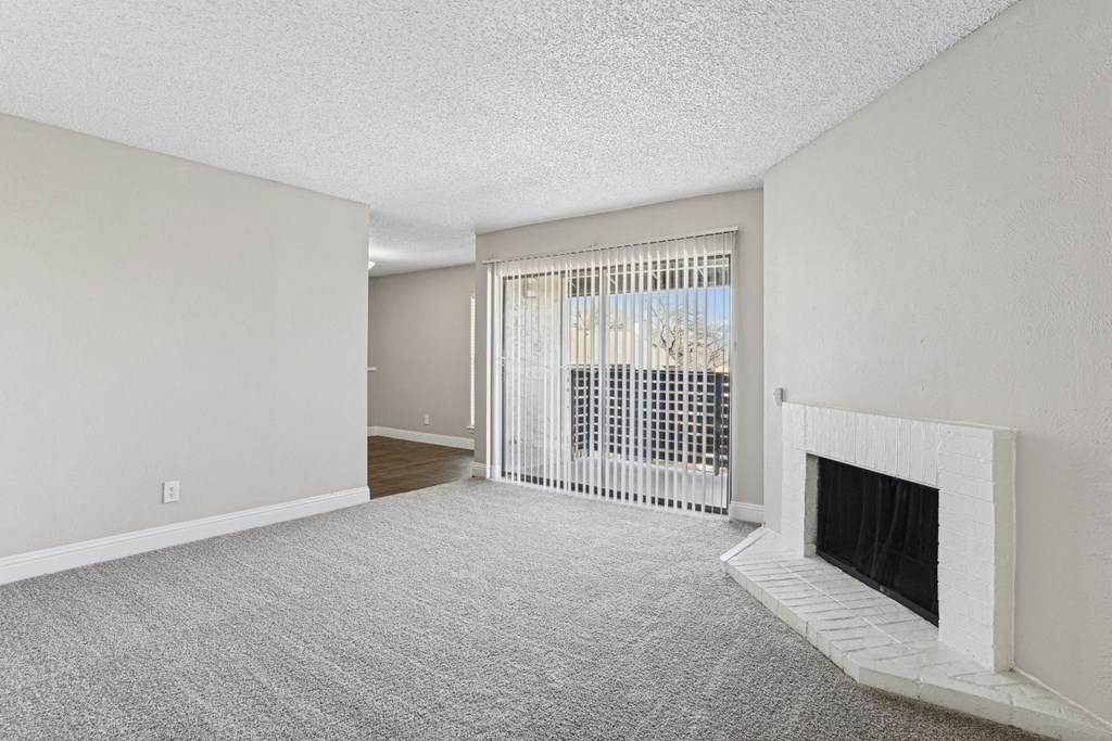 B1 Living room with a fireplace and a window with blinds at Vine Apartments in Arlington, TX