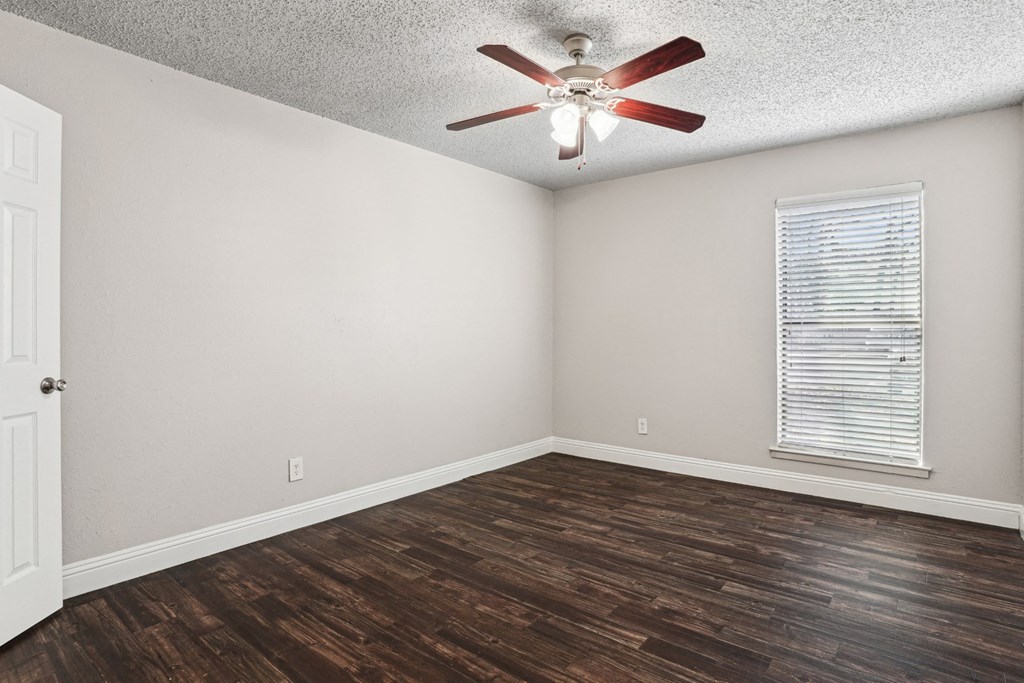 Upgraded A1 bedroom with a ceiling fan and a window with blinds at Vine Apartments in Arlington, TX