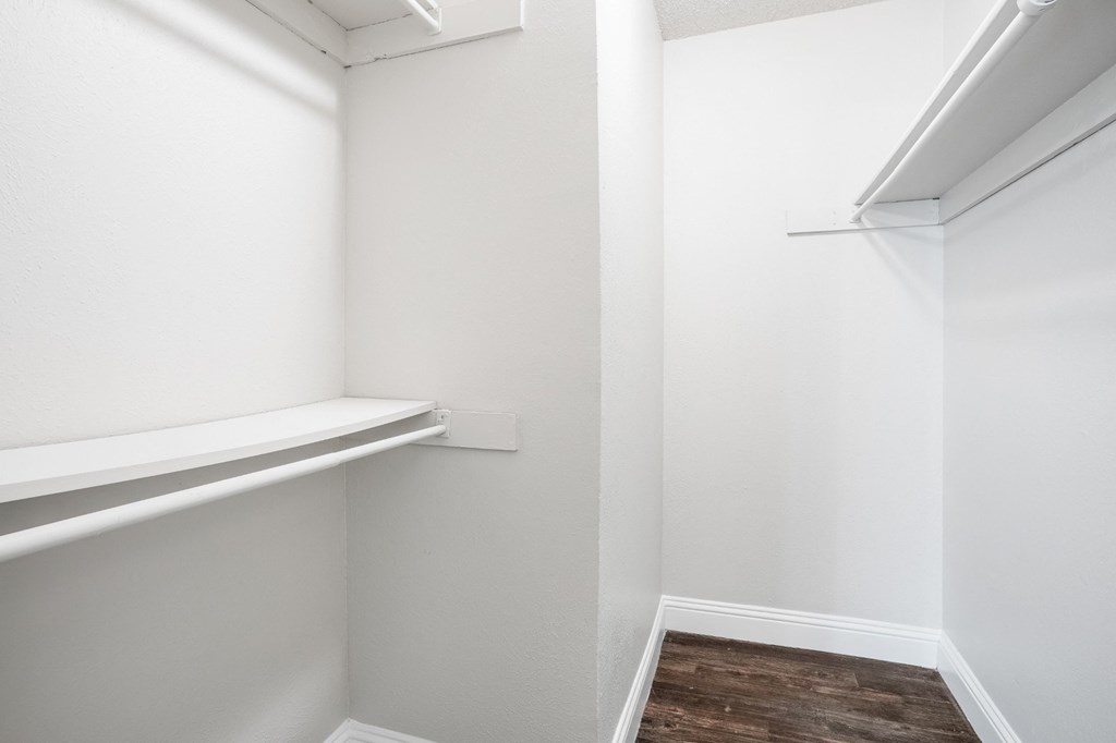 Upgraded A1 white closet with a shelf and a wooden floor at Vine Apartments in Arlington, TX