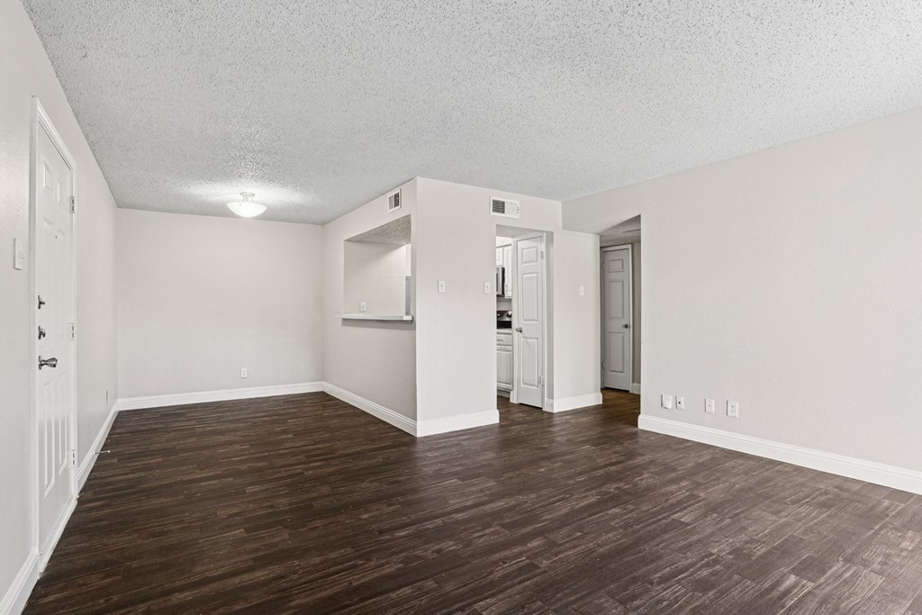 Upgraded A1 living room with wooden floors and white walls at Vine Apartments in Arlington, TX