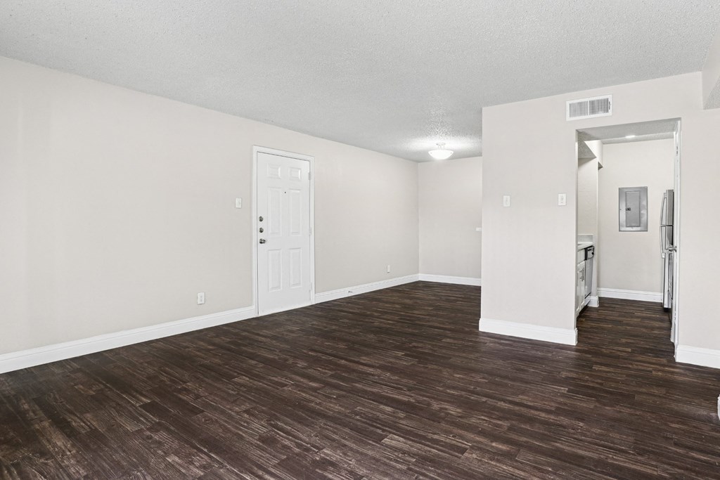 Upgraded A1 living room with a wooden floor and white walls at Vine Apartments in Arlington, TX