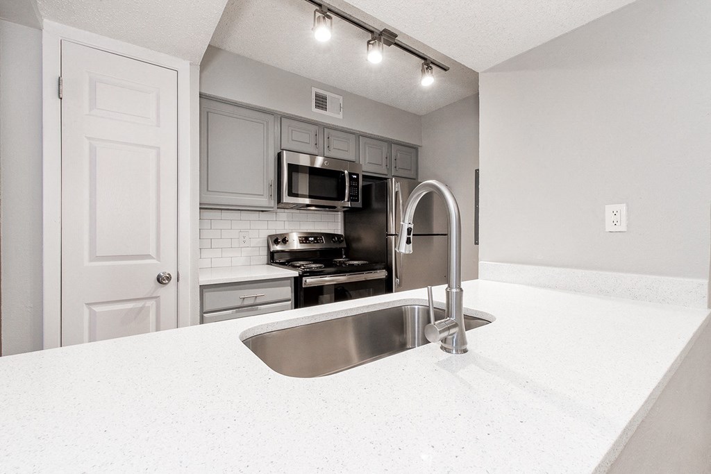 A2 upgraded apartment kitchen with a stainless steel sink and white countertop at Vine Apartments in Arlington, TX