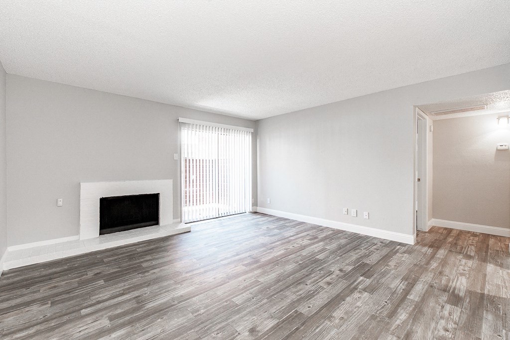 A2 upgraded living room with a fireplace and sliding door leading to balcony at Vine Apartments in Arlington, TX