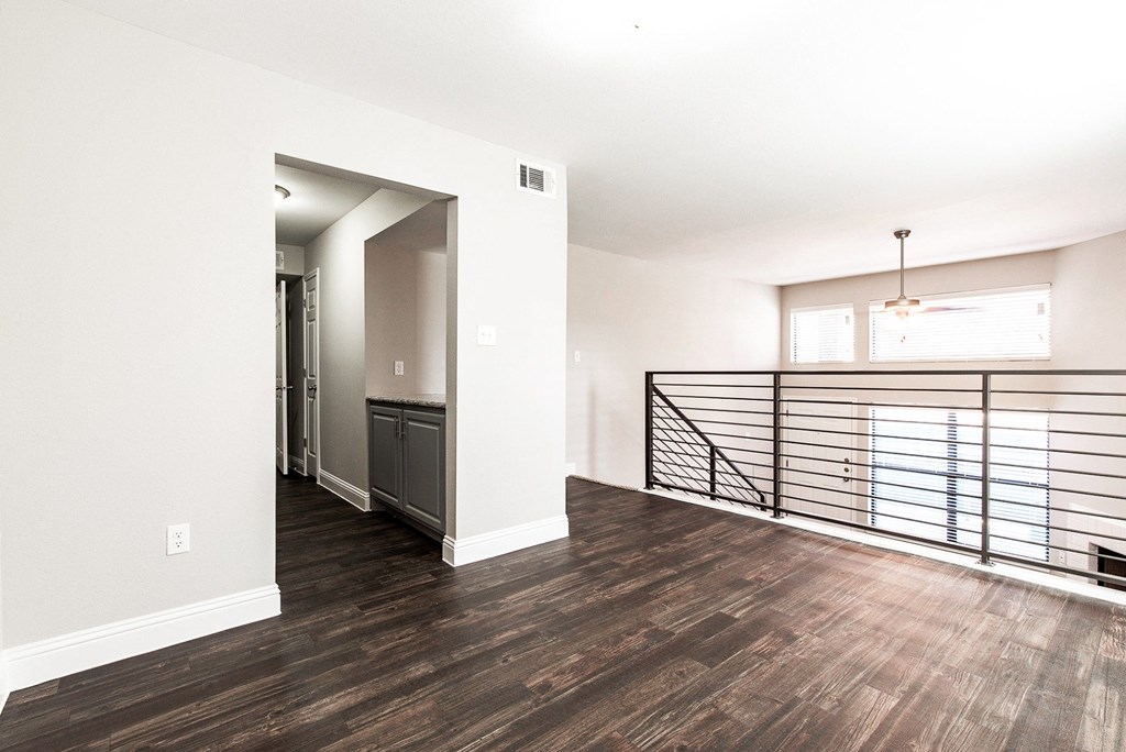A4 apartment dining room next to kitchen with a metal railing overlooking living room and entrance at Vine Apartments in Arlington, TX