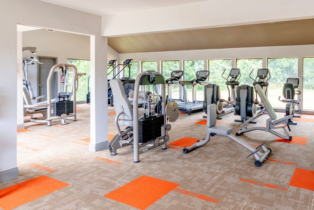 A gym with orange mats and a variety of exercise equipment at Vine Apartments in Arlington, TX