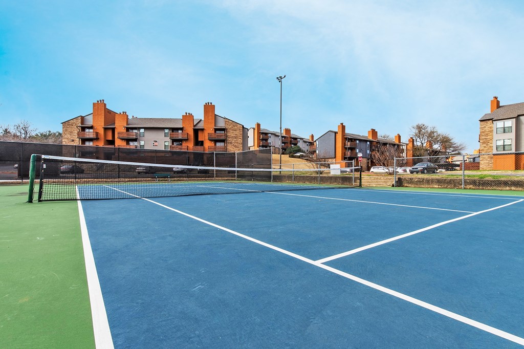 A tennis court with a green border and white lines at Vine Apartments in Arlington, TX