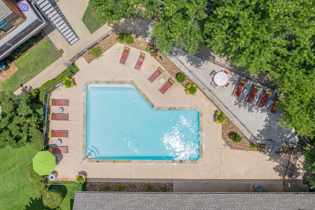 An aerial view of a swimming pool surrounded by trees and a parking lot at Vine Apartments in Arlington, TX
