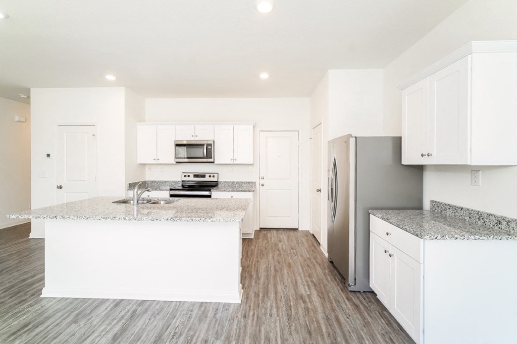 a kitchen with white cabinets and granite countertops at Beacon at Meridian, San Antonio Texas