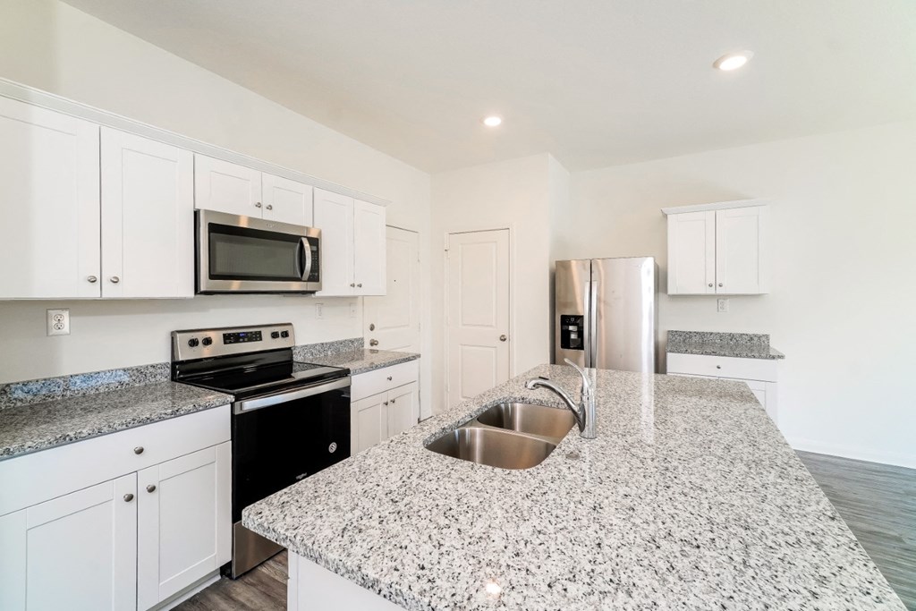a kitchen with white cabinets and granite countertops at Beacon at Meridian, San Antonio, 78245