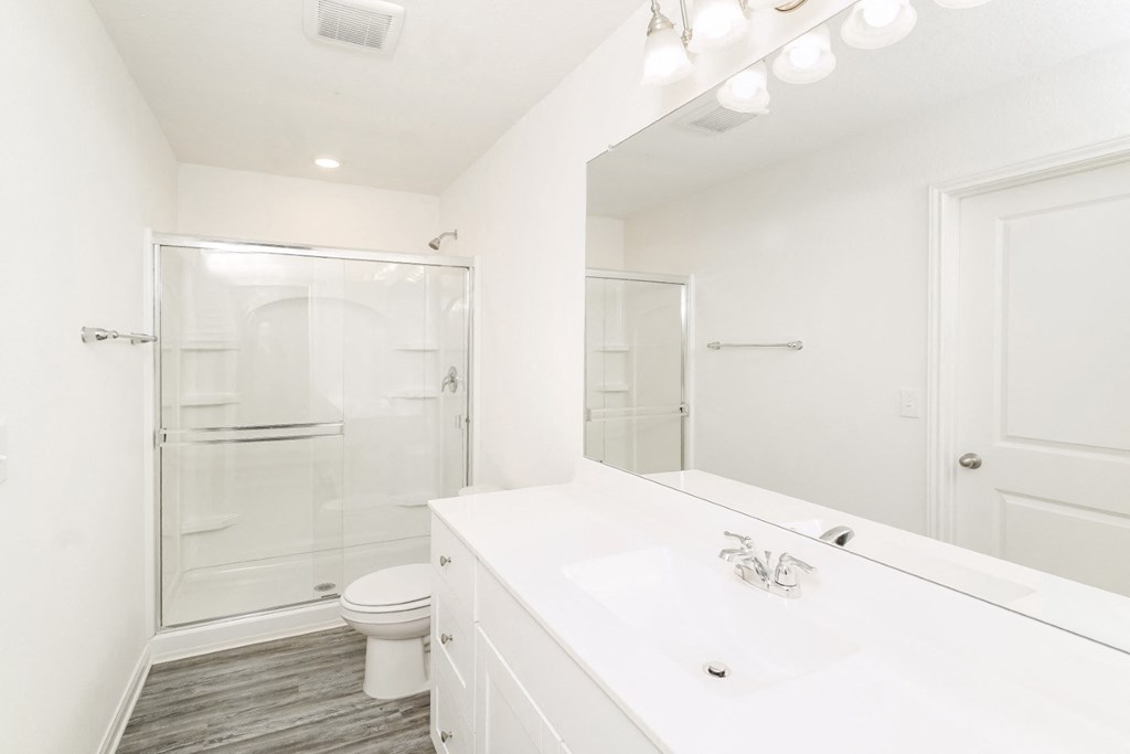 a bathroom with white cabinets and shower