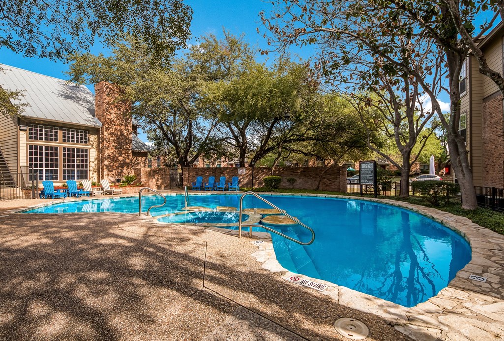 a swimming pool with chairs around it in front of a house