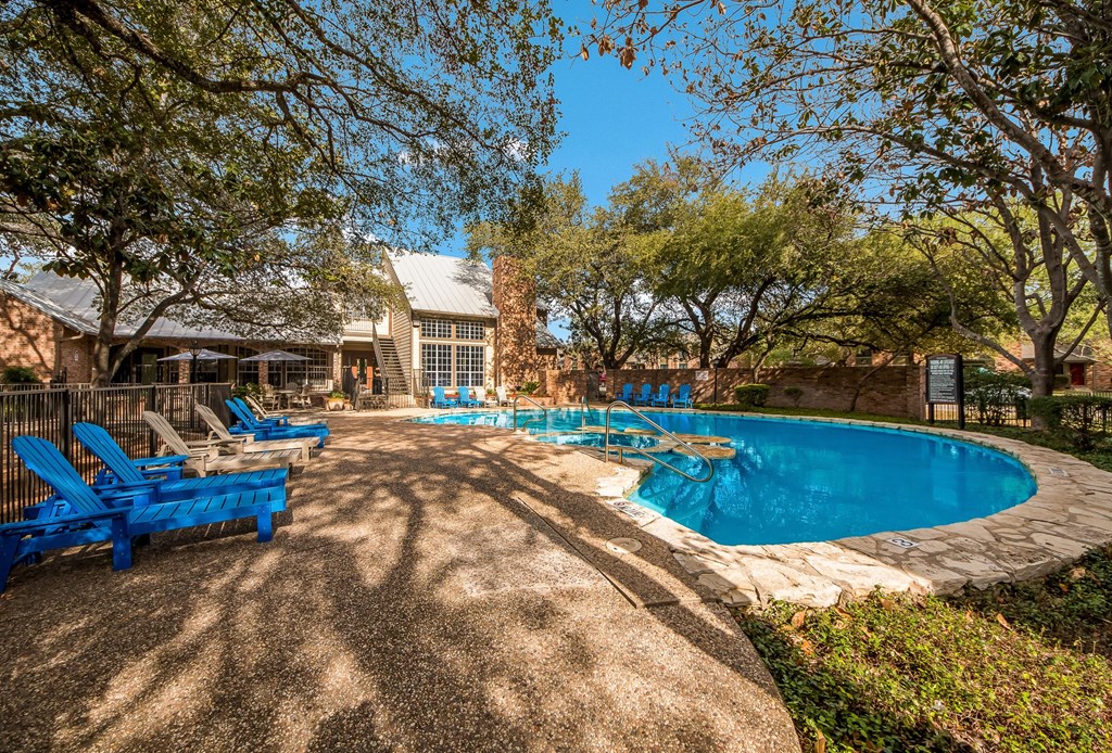 a swimming pool with blue chairs next to a house