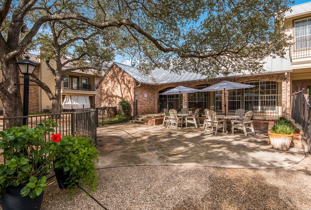 a patio with tables and umbrellas in front of a house