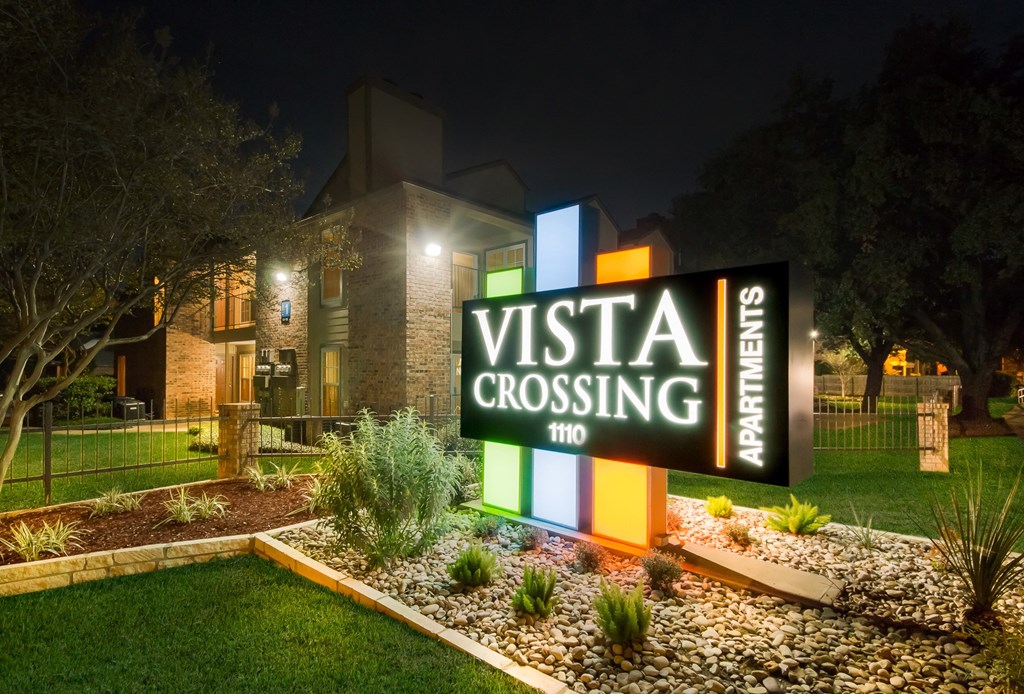 a night view of a vista crossing sign in front of a building