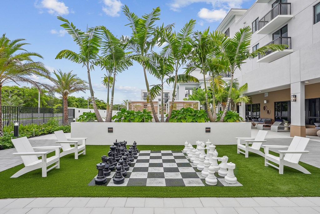 a large chess board is set up on a lawn in front of a building at Westgate on University in Lauderhill, FL