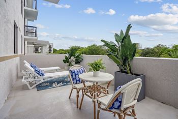 a patio with a table and chairs and two chaise lounges at Westgate on University in Lauderhill, FL