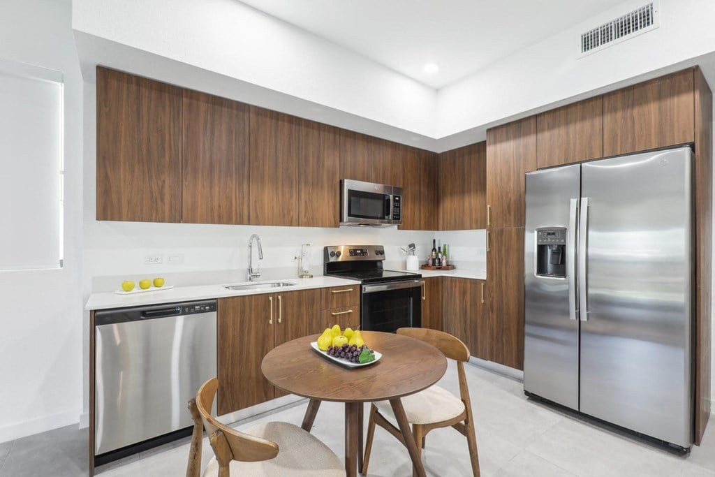 Kitchen with stainless steel appliances and a wooden table in A2 Floor Plan at Westgate on University in Lauderhill, FL