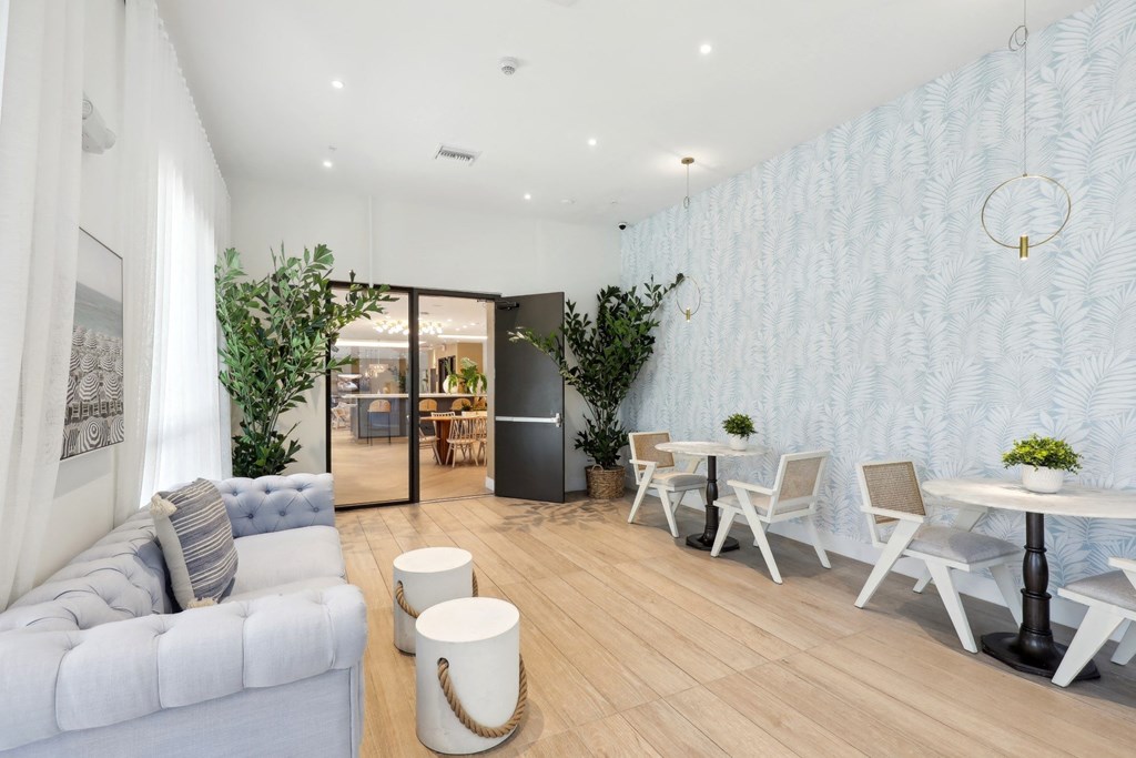 Clubhouse space with 2-person tables and a couch at Westgate on University in Lauderhill, FL