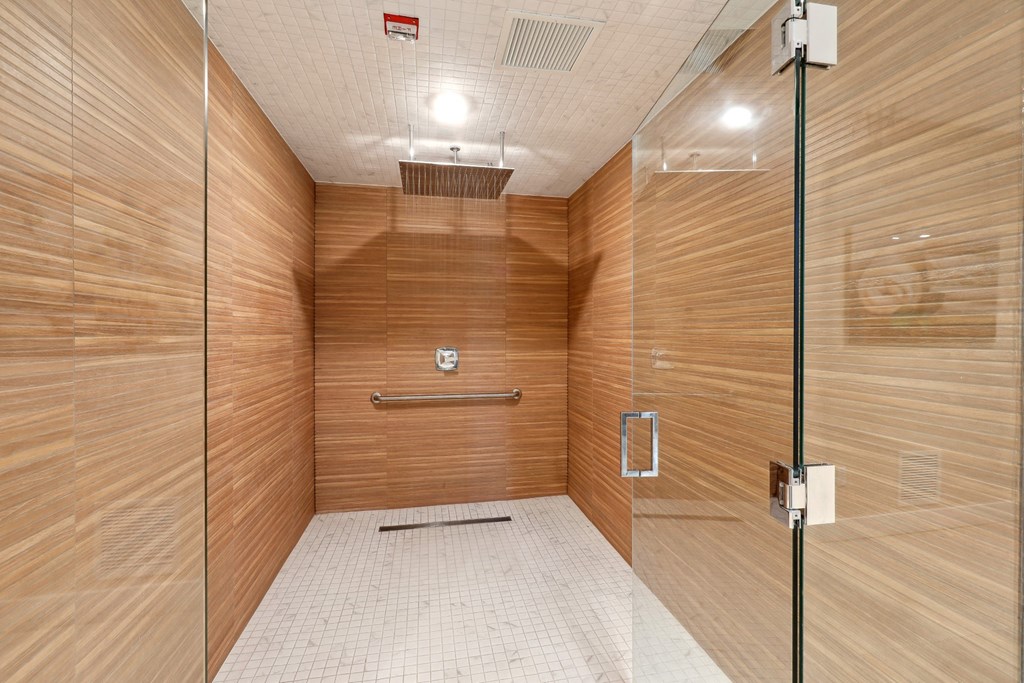 Shower area with wooden walls and  glass doors at Westgate on University in Lauderhill, FL