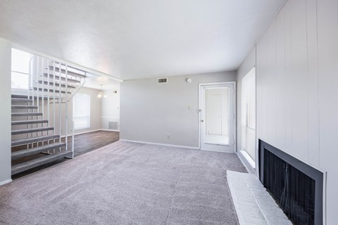A spacious room with a fireplace and a staircase.