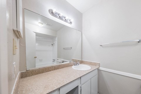 A bathroom with a sink, mirror, and a white door.