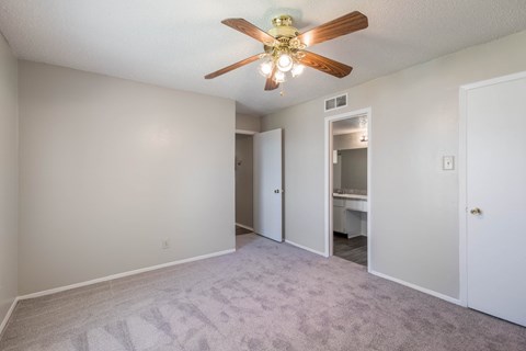 A room with a ceiling fan and carpeted floor.