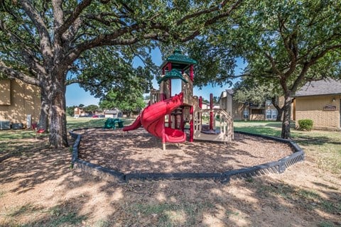 A playground with a red slide and a green roof.