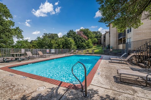 A swimming pool surrounded by trees and a building.