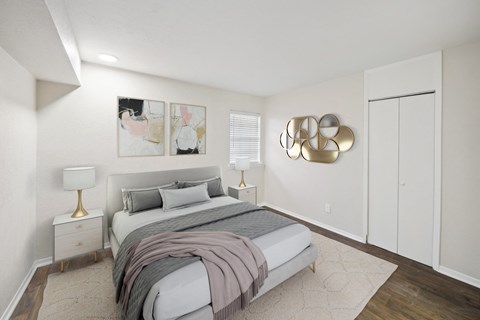 a bedroom with white walls and a bed with grey blankets and pillows at Woodlands of Plano in Plano, TX