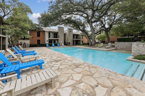 A pool surrounded by blue and white lounge chairs at Westdale Pointe in Austin, TX