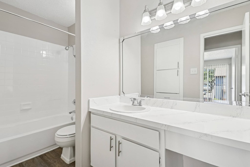 A5 bathroom with a toilet, sink, and mirror at Windridge on the Parkway apartments in Dallas, TX