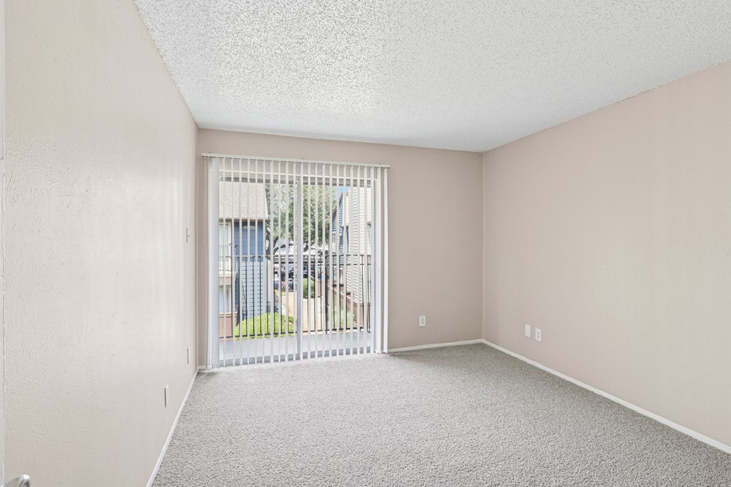 A5 bedroom with a carpeted floor and a sliding glass door leading to a balcony at Windridge on the Parkway in Dallas, TX