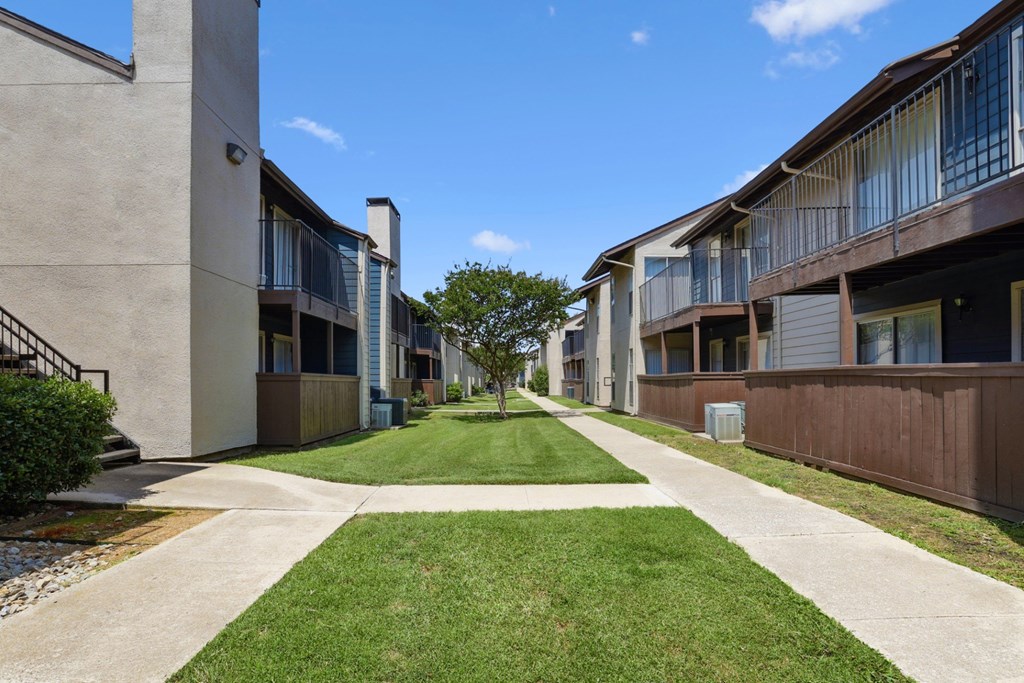 An area of grass and sidewalks between apartment buildings at Windridge on the Parkway in Dallas, TX