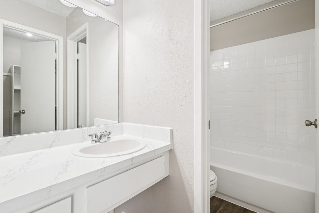 B6 white bathroom with a sink, bathtub, and a mirror at Windridge on the Parkway in Dallas, TX