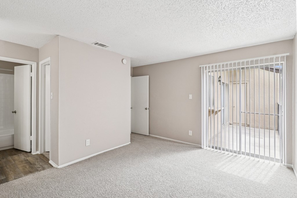 Carpeted B6 bedroom with a glass sliding door leading to a balcony at Windridge on the Parkway in Dallas, TX