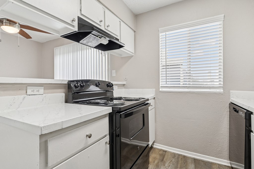 B6 kitchen with a black stove top oven and white cabinets at Windridge on the Parkway in Dallas, TX