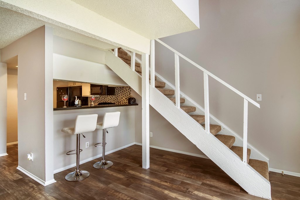 a bar under the stairs in a home with wood floors