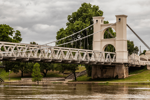 A white bridge with a metal railing crosses over a body of water.