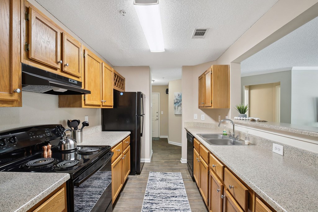 Model apartment kitchen with wood cabinets and black appliances at Wellington Ridge in Lawrenceville, GA