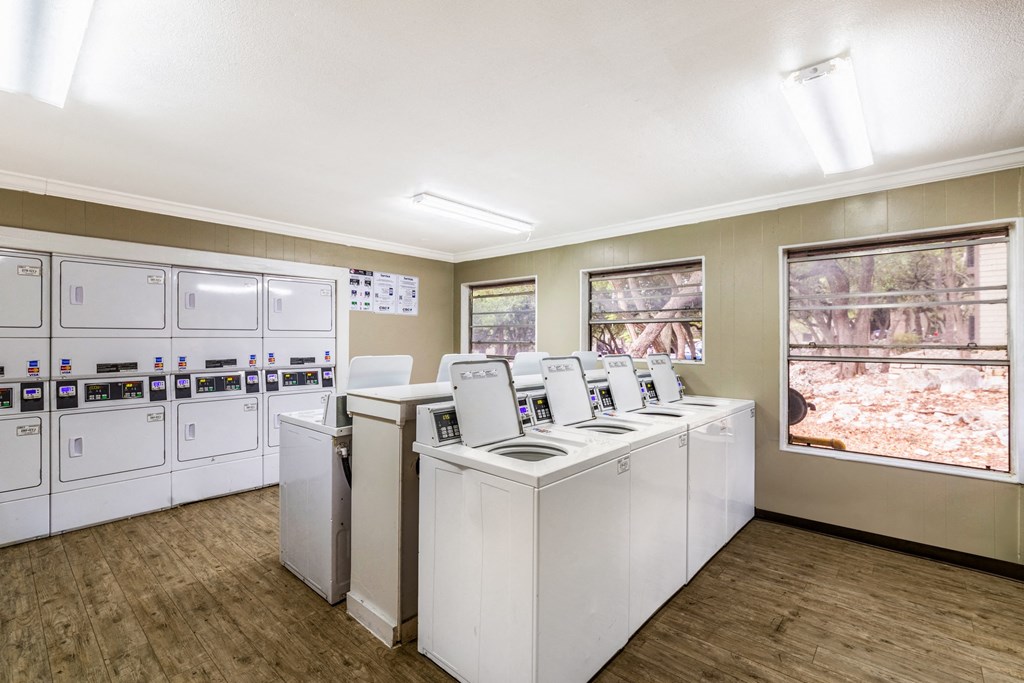 a laundry room with washers and dryers and a row of washing machines
