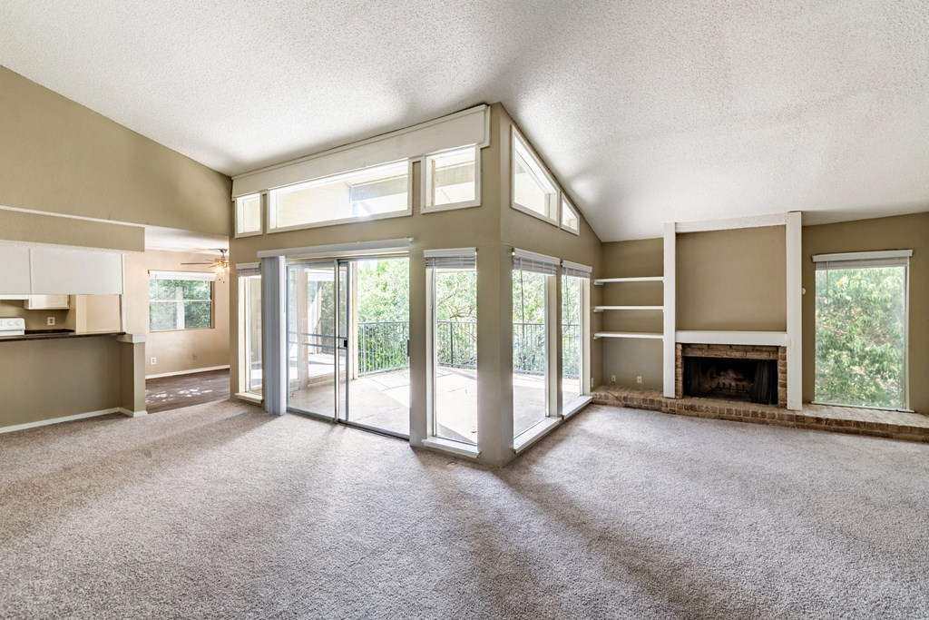 an empty living room with a fireplace and glass doors