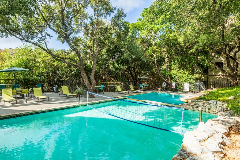 a swimming pool with trees and chairs around it