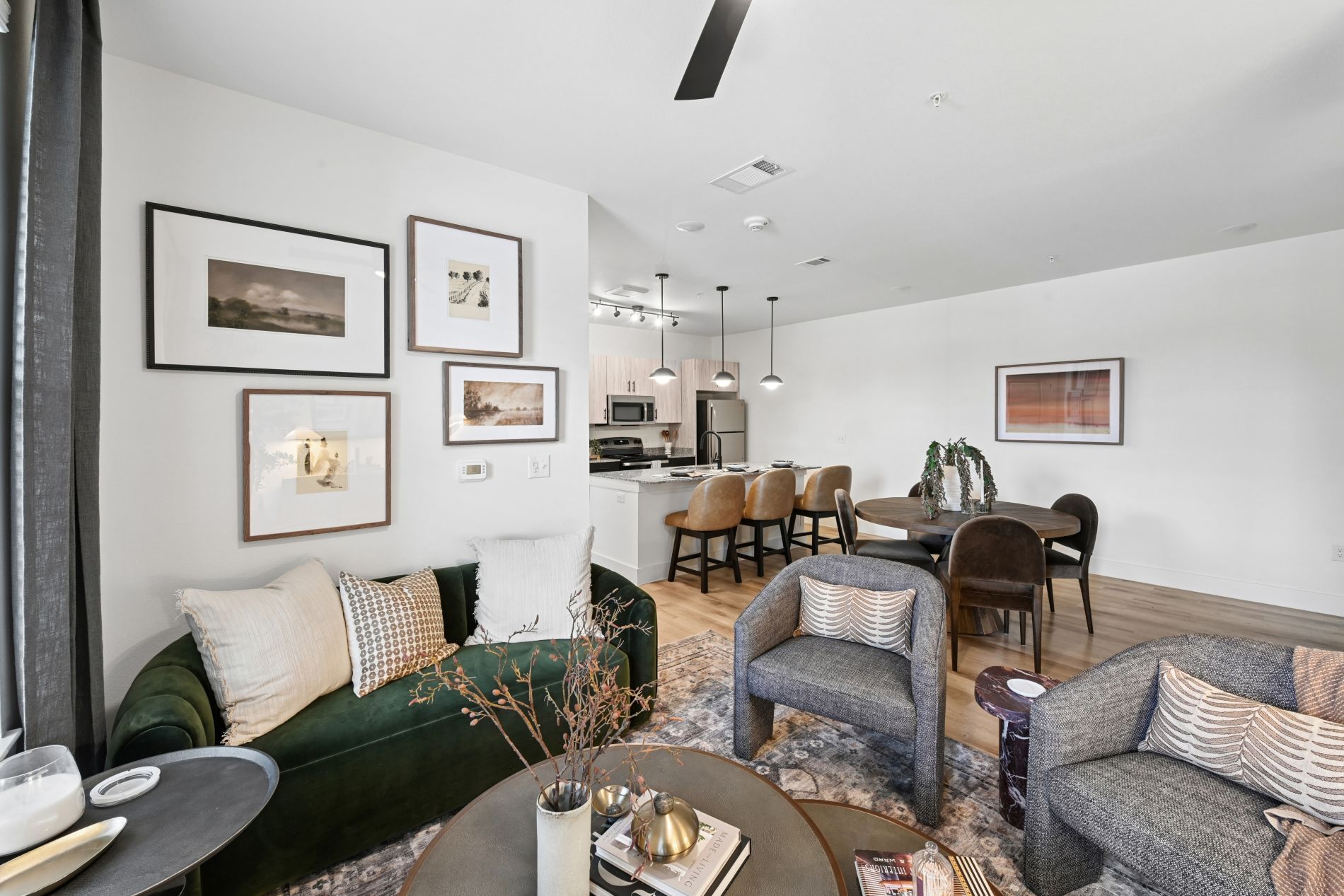 A living room with a green couch, a grey couch, a coffee table, and a dining table with chairs.