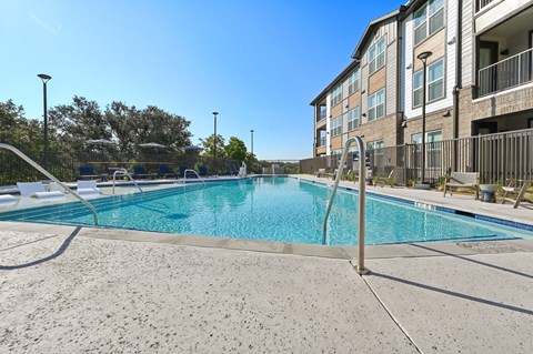 A swimming pool in front of a building with a clear blue sky.