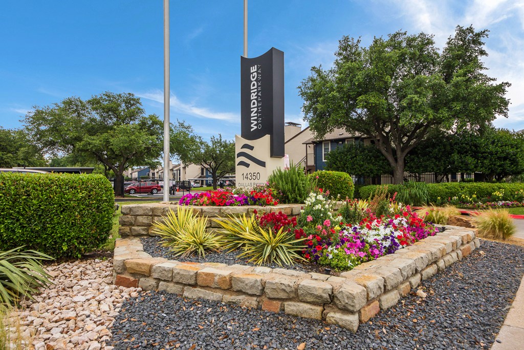 a stone retaining wall with flowers and plants in front of a building