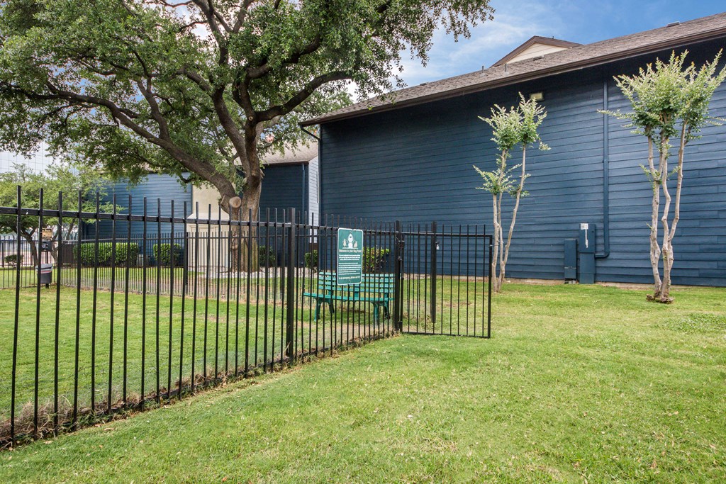 a blue building with a fence and a green bench in a yard