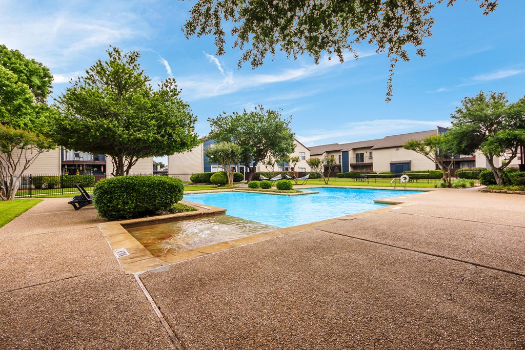 a swimming pool with trees and a building in the background