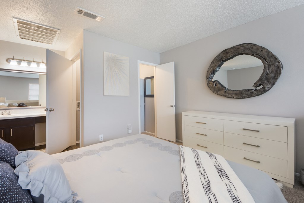 a bedroom with a bed and a mirror and a bathroom