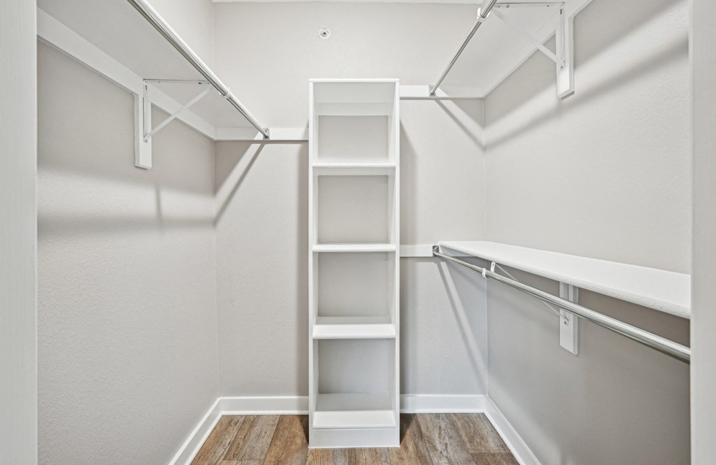A spacious walk in closet with white shelves at Windridge On The Parkway Apartments in Dallas, TX